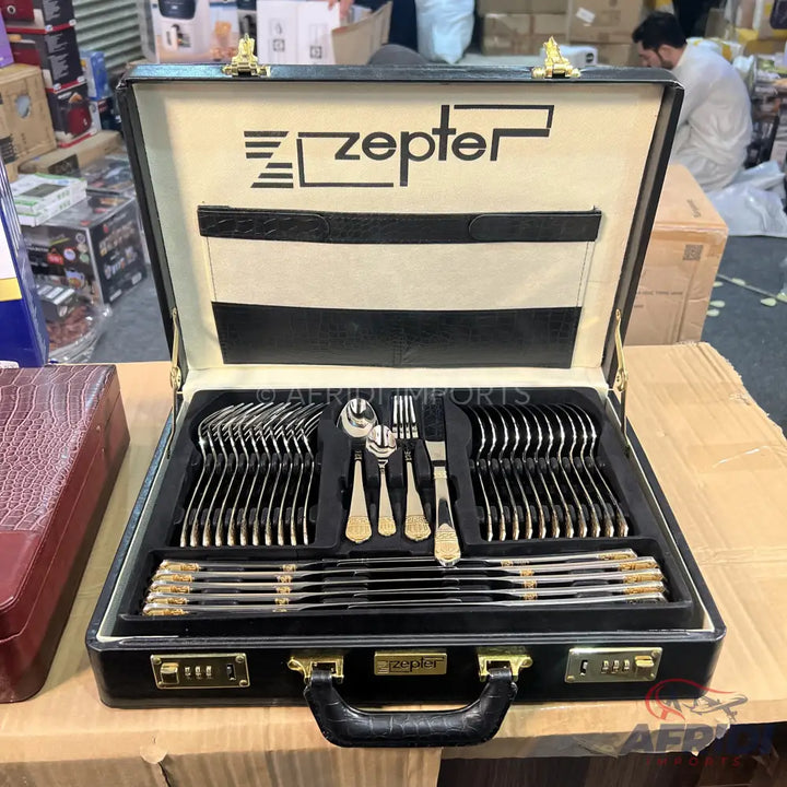 Black briefcase-style box containing a full cutlery set with gold accents.