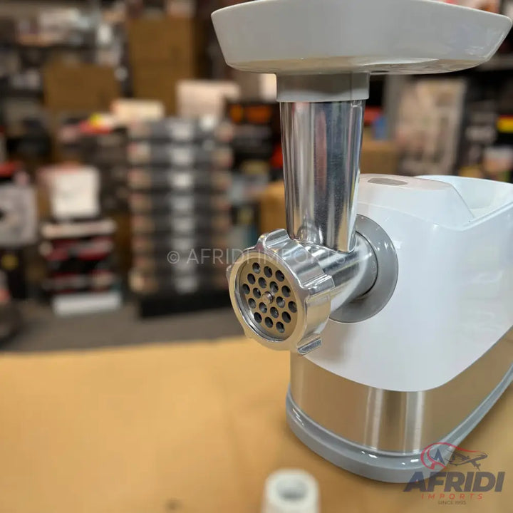 A white and silver electric meat grinder with a feeding tray and a metal grinding plate.