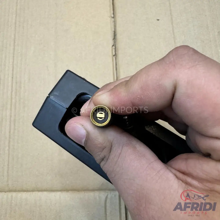 A person’s hand holding a black device with a golden-tipped nozzle.
