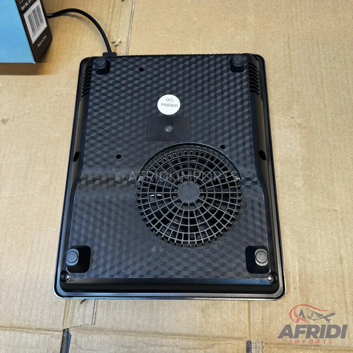 Black, square-shaped induction cooktop with a textured bottom, a central cooling fan, and four rubber feet.