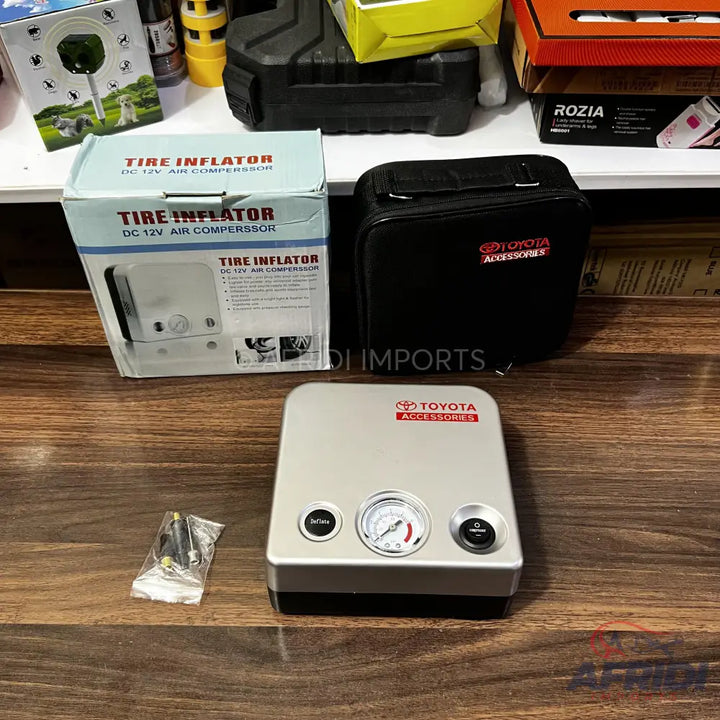 A portable silver and black Toyota 12V DC tire inflator with an analog pressure gauge.