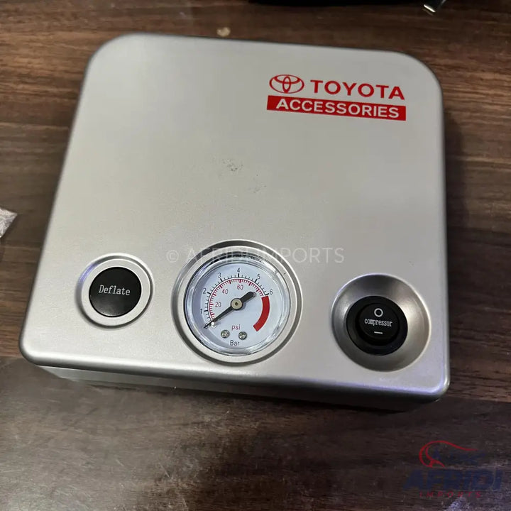 Silver portable tire inflator with a pressure gauge and two control buttons.