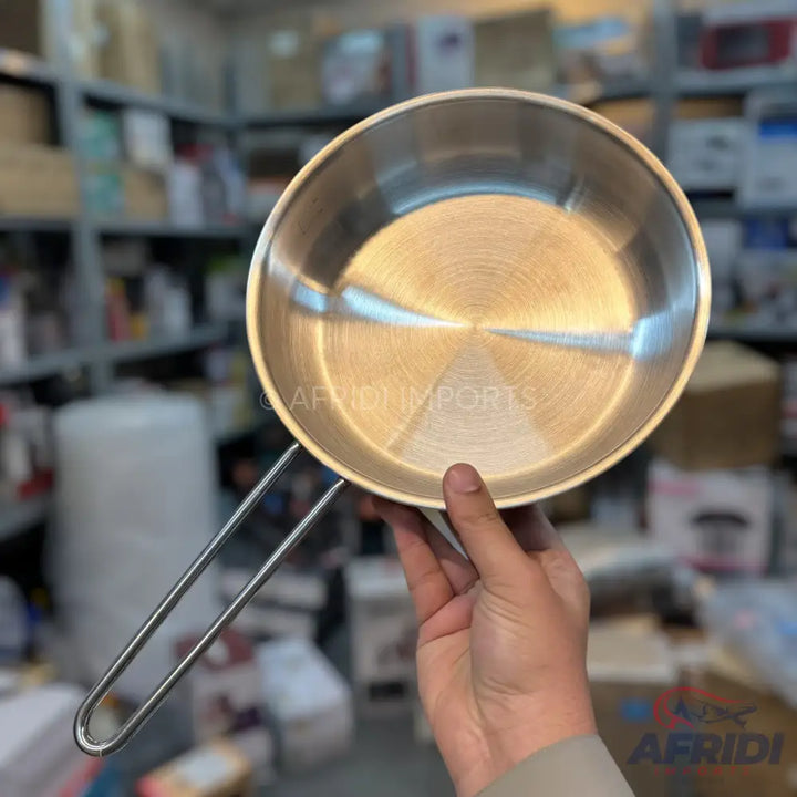 Shiny stainless steel frying pan with a long, thin wire handle.