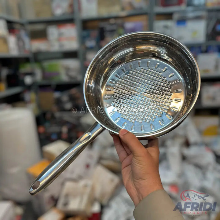 Shiny stainless steel saucepan with a perforated grater insert.