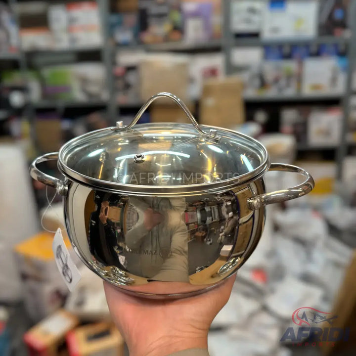 Shiny stainless steel cooking pot with a glass lid and two handles.
