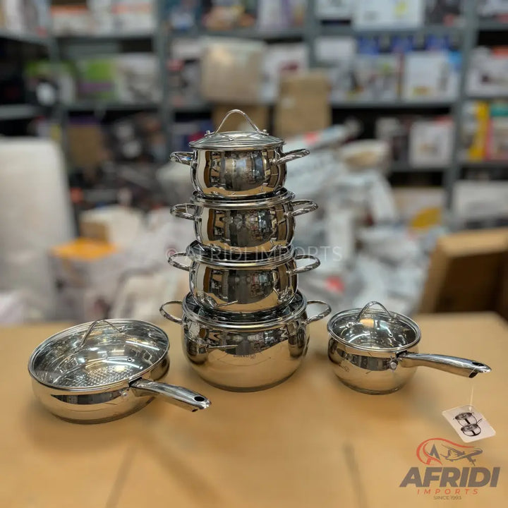A set of shiny stainless steel pots and pans with clear glass lids.