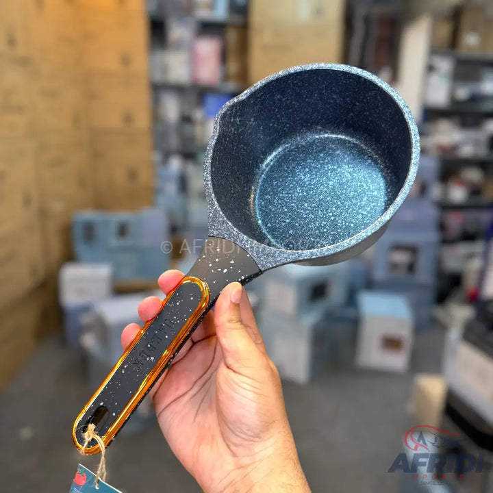 Black speckled non-stick saucepan with a gold-trimmed handle.