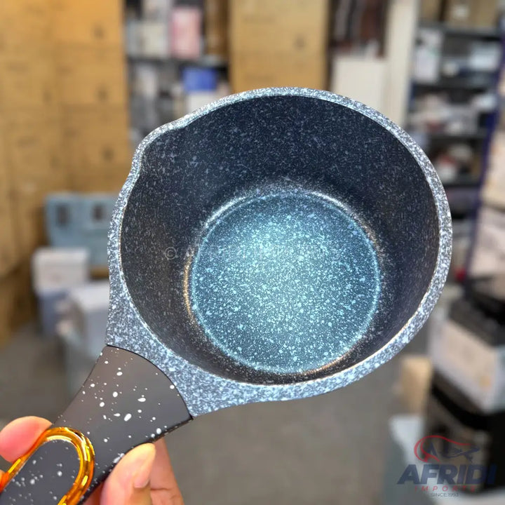 A speckled grey and black non-stick saucepan with a pour spout and a handle with gold accents.