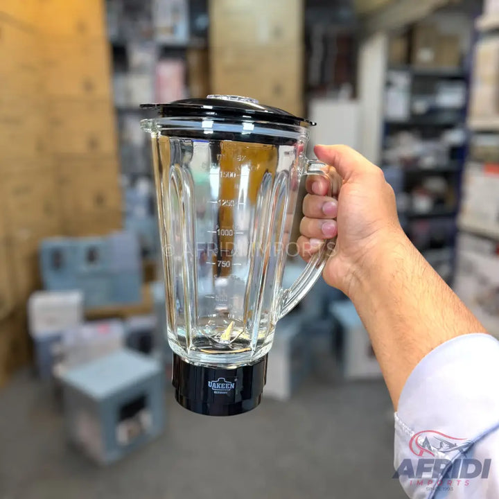 Clear glass blender jar with a black lid and base, featuring measurement markings and a built-in blade.