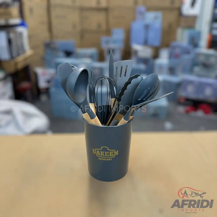 A set of silicone kitchen utensils with wooden handles in a dark gray holder.
