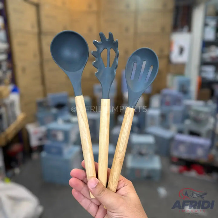 A set of three silicone kitchen utensils with wooden handles, including a ladle, a spaghetti server, and a slotted spoon.