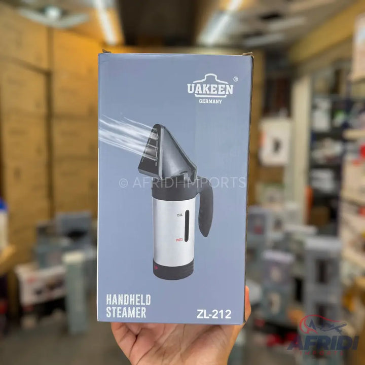 A handheld garment steamer with a grey and silver body, a black handle, and a transparent water tank.