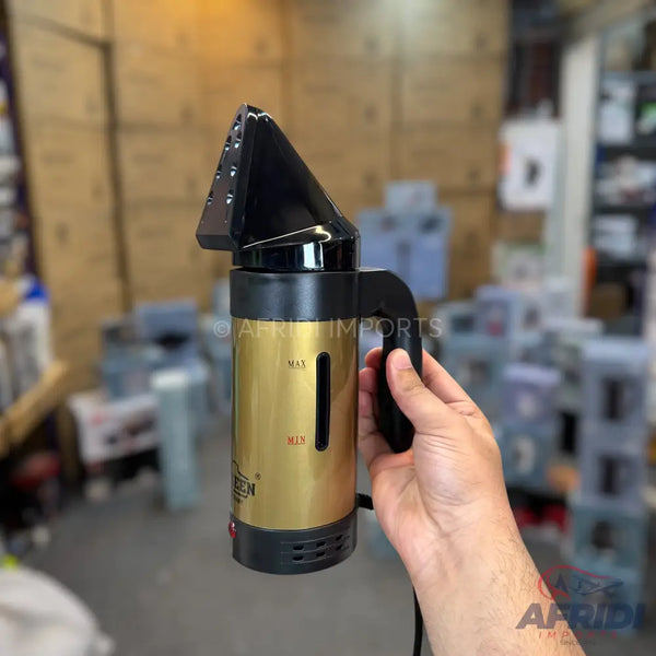 A handheld gold and black garment steamer with a visible water level indicator.