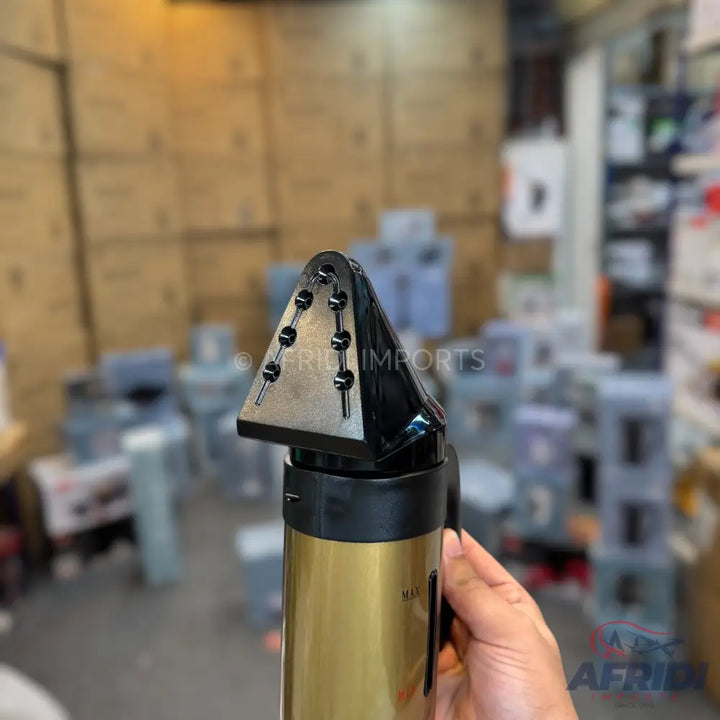 Gold and black handheld garment steamer with a triangular head.