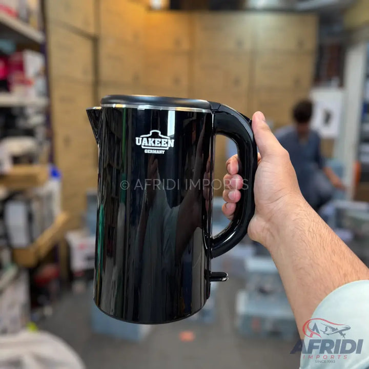 Black electric kettle with a handle.