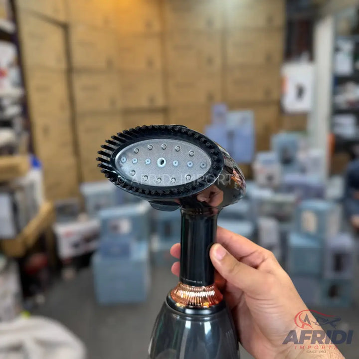 Black and rose gold handheld garment steamer with a brush attachment.