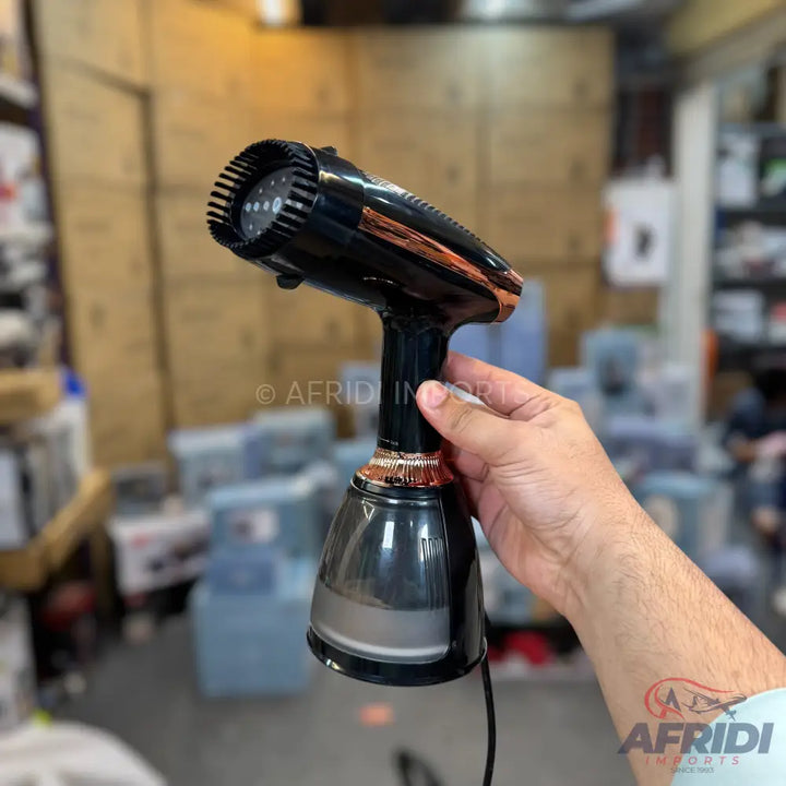 Handheld black and copper garment steamer with a clear water tank.