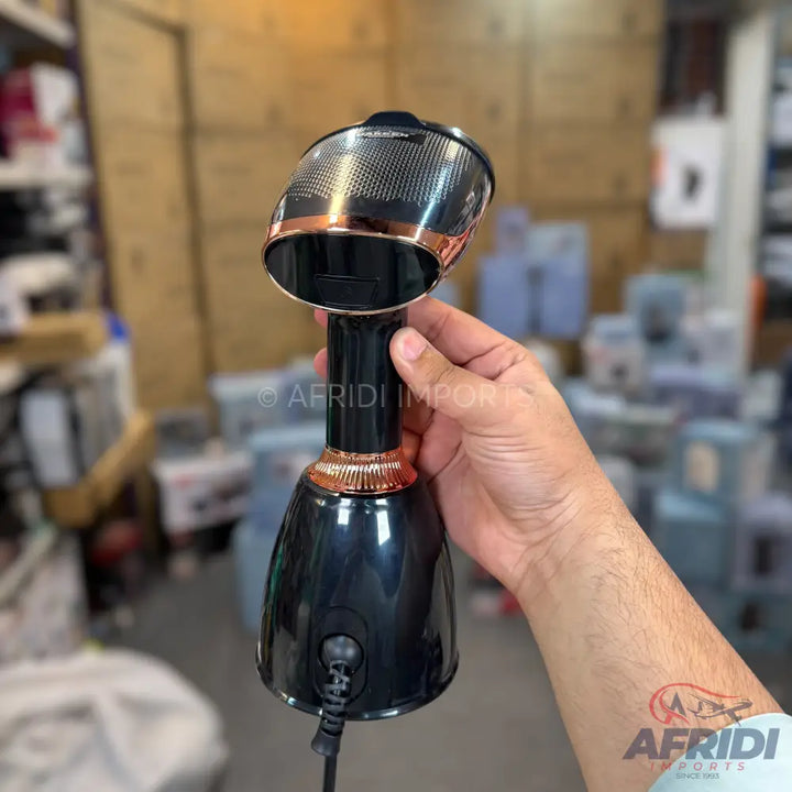 Black and rose gold handheld garment steamer with a perforated head.