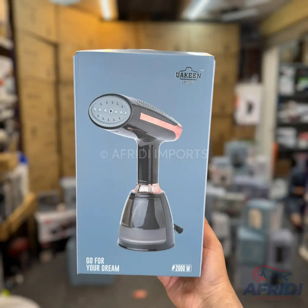 Handheld garment steamer with a dark body and rose gold accents.