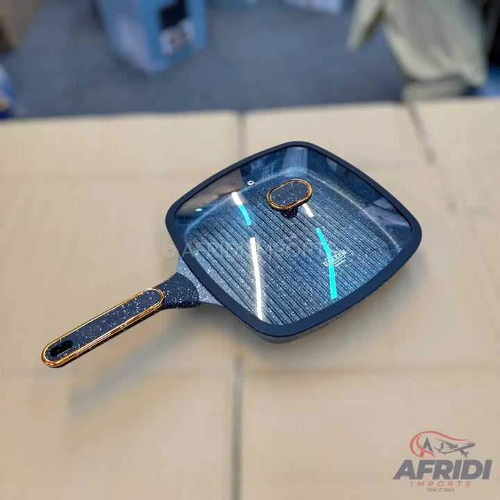 Square black grill pan with a glass lid and a speckled handle.