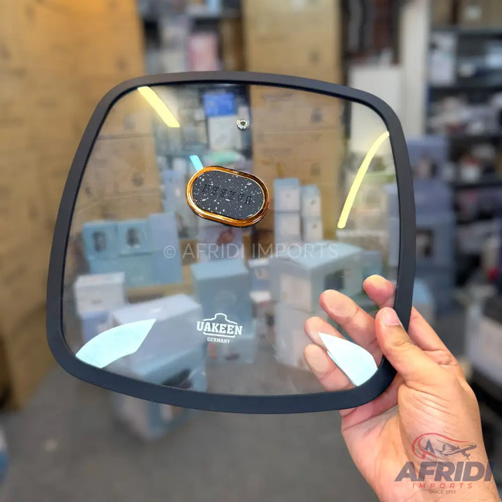 A transparent glass pot lid with a black rim and an oval-shaped handle.