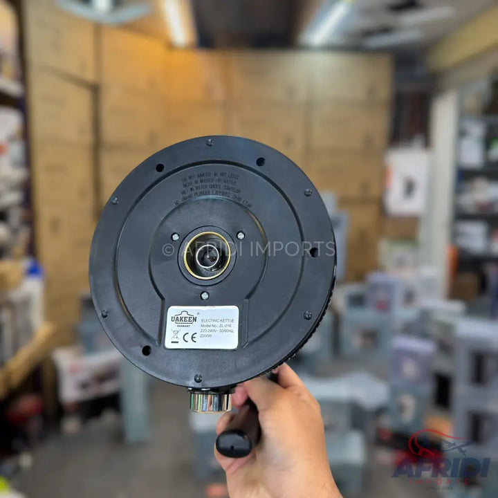 Black electric kettle base held by a hand.