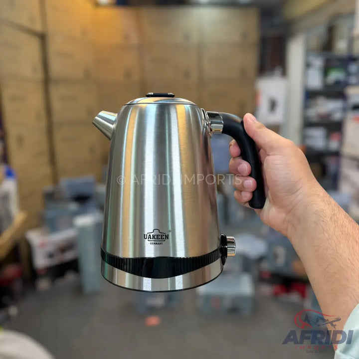 Stainless steel electric kettle with a black handle.