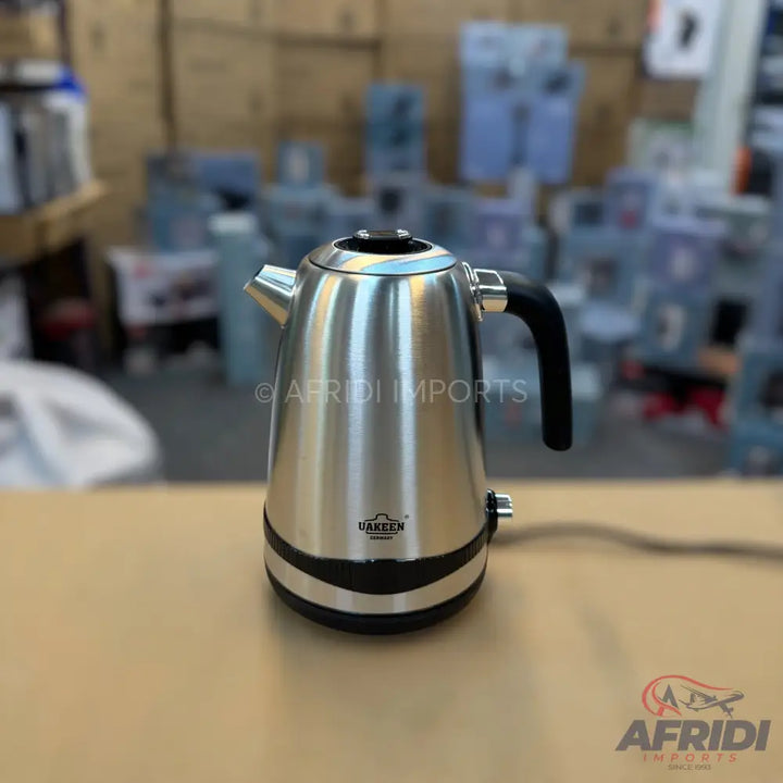 A stainless steel electric kettle with a black handle and base.