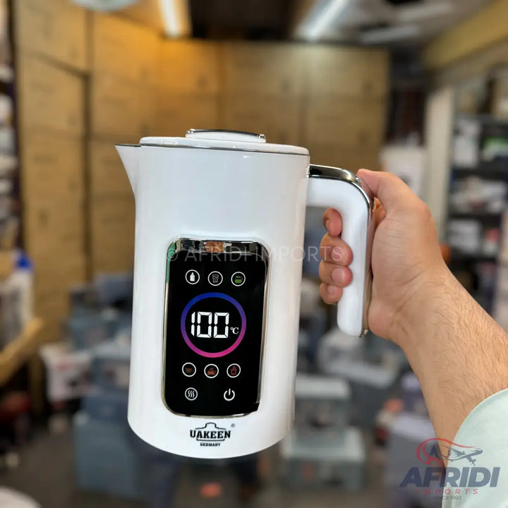 White electric kettle with a digital display showing a temperature of 100°C and various control icons.