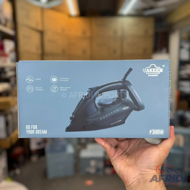 A dark grey steam iron with a black handle, featuring an anti-drip system, self-cleaning function, and a 3000W power rating.
