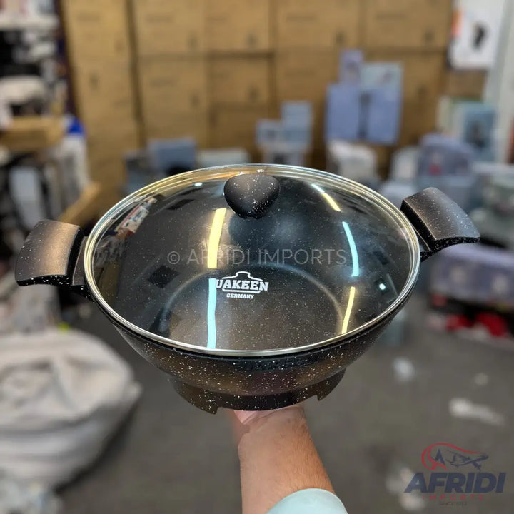 Black speckled non-stick cooking pot with a glass lid and two handles.