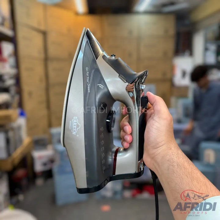 A silver and black steam iron with a black power cord.