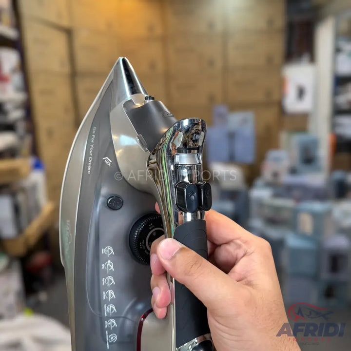 A person holding a grey and black handheld clothes steamer.