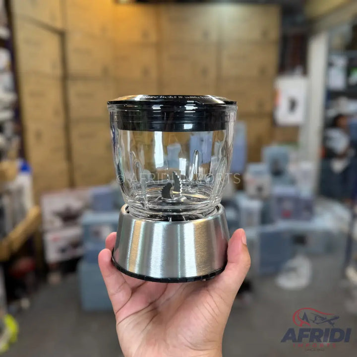 A clear glass blender jar with a black lid and a brushed metal base, containing a two-pronged blade.