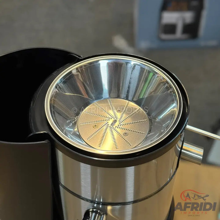 A stainless steel juice extractor with a clear plastic lid.