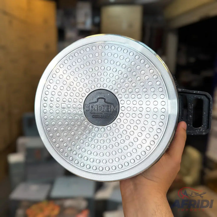 The underside of a speckled cooking pot with a textured, circular base.