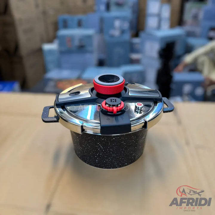 Black and silver speckled pressure cooker with red accents.