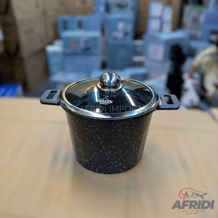Black speckled cooking pot with a glass lid and two side handles.