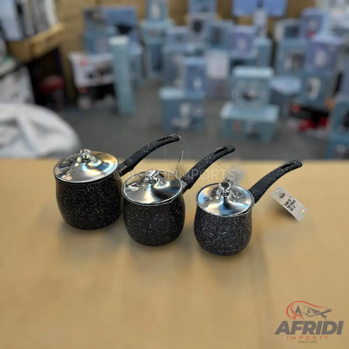 A set of three black speckled nonstick saucepans with matching lids and long black handles.