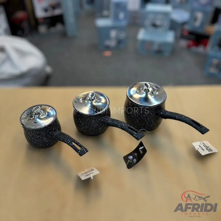 Set of three black speckled saucepans with silver lids and handles.