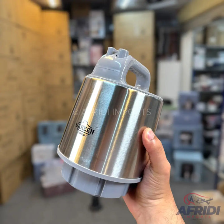 A handheld, stainless steel blender with a grey plastic top and handle.