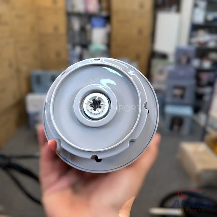 A white plastic cylindrical base with a star-shaped screw in the center.