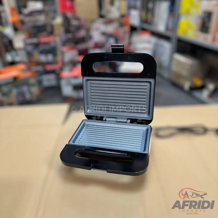 An open black electric sandwich maker or grill with ridged non-stick plates.