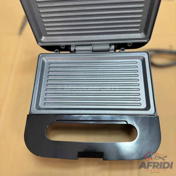 An open, dark-grey electric sandwich maker with ridged cooking plates.