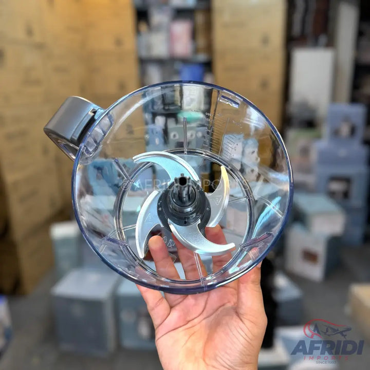 A clear plastic food processor bowl with a four-blade chopping attachment.