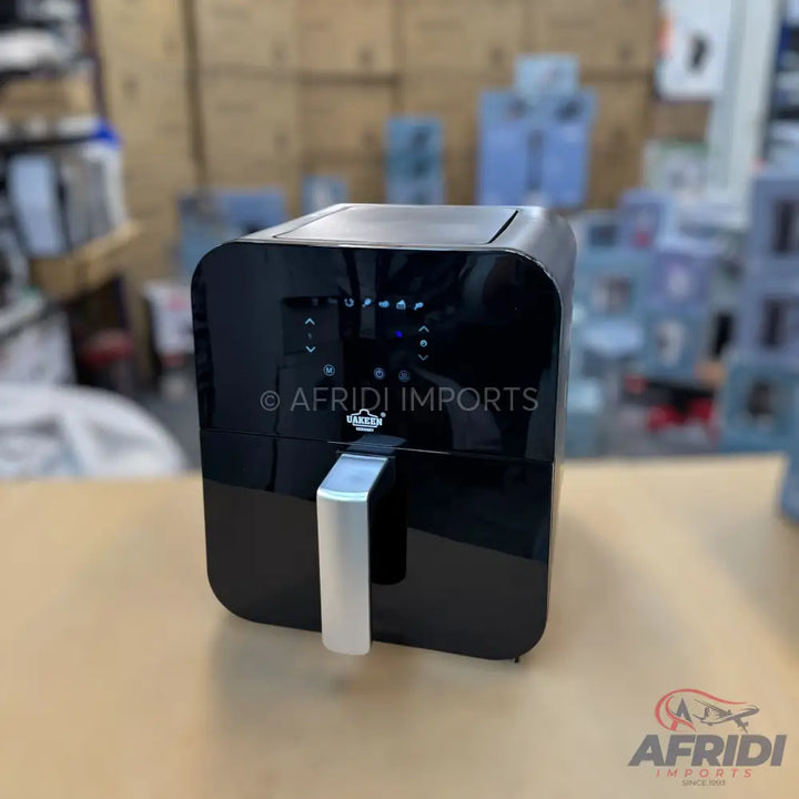 Black digital air fryer with a silver handle.