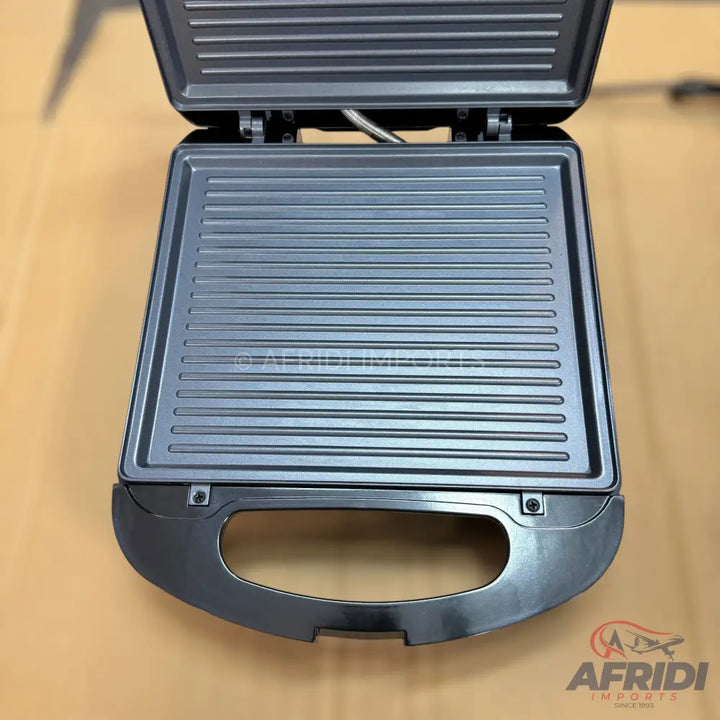 An open, dark grey electric grill with ridged cooking plates.
