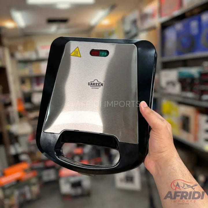 Stainless steel sandwich maker with black trim and indicator lights.