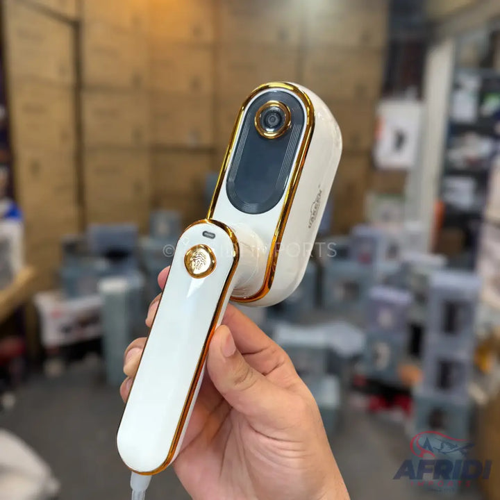 A white and gold handheld lint remover with a built-in camera.