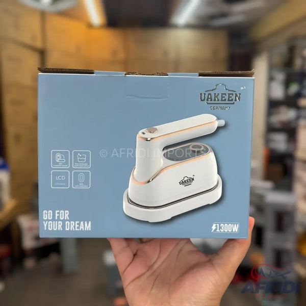 White and rose gold portable steam iron with a foldable handle.